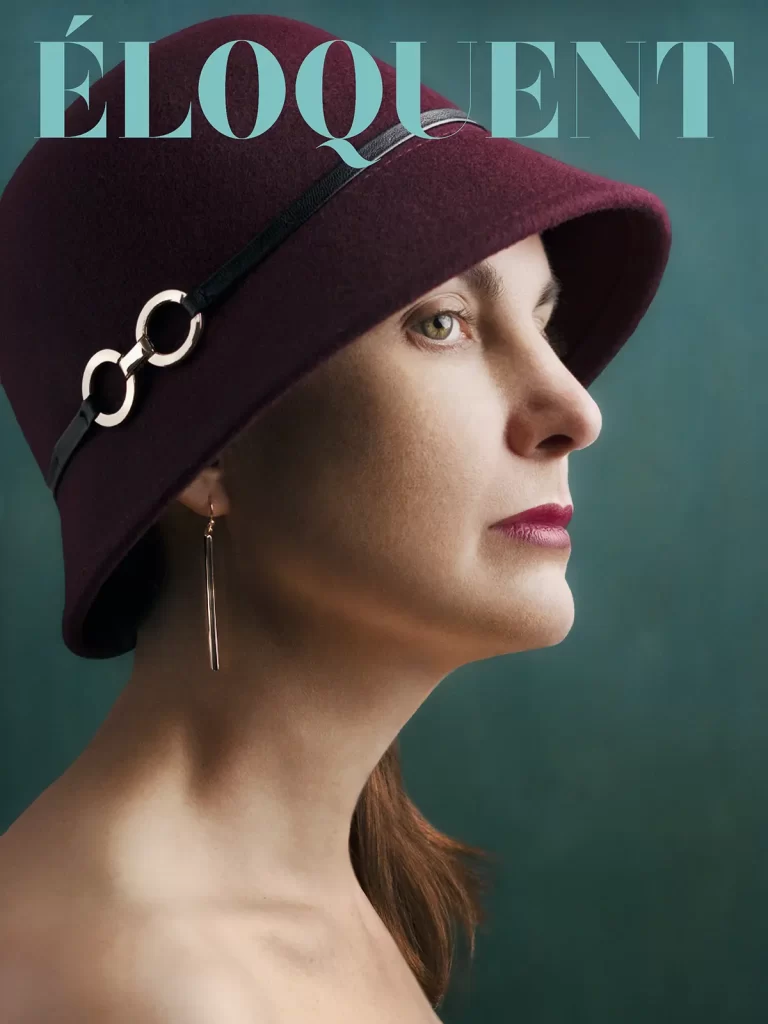 Eloquent magazine cover. Woman wearing a maroon hat on a teal background.