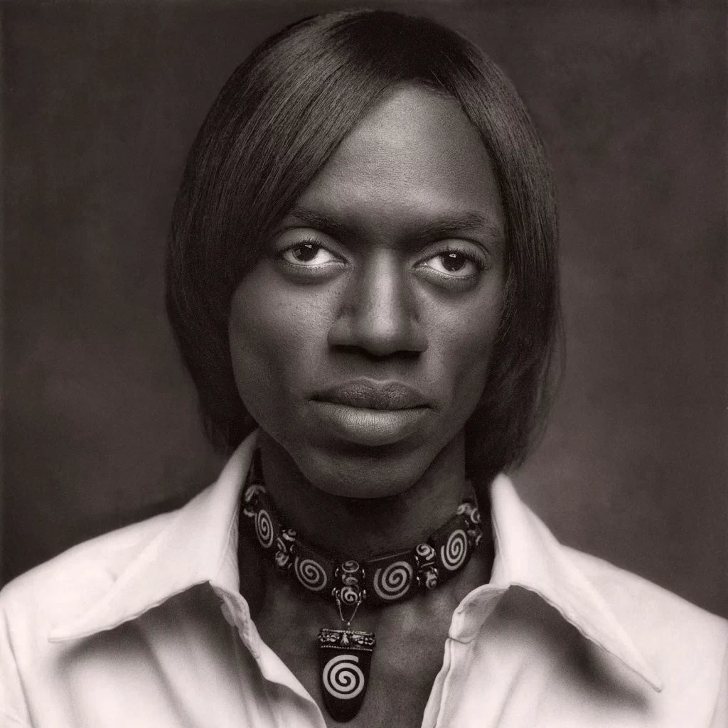 Black and white portrait of a young African American man wearing a wide graphic necklace.