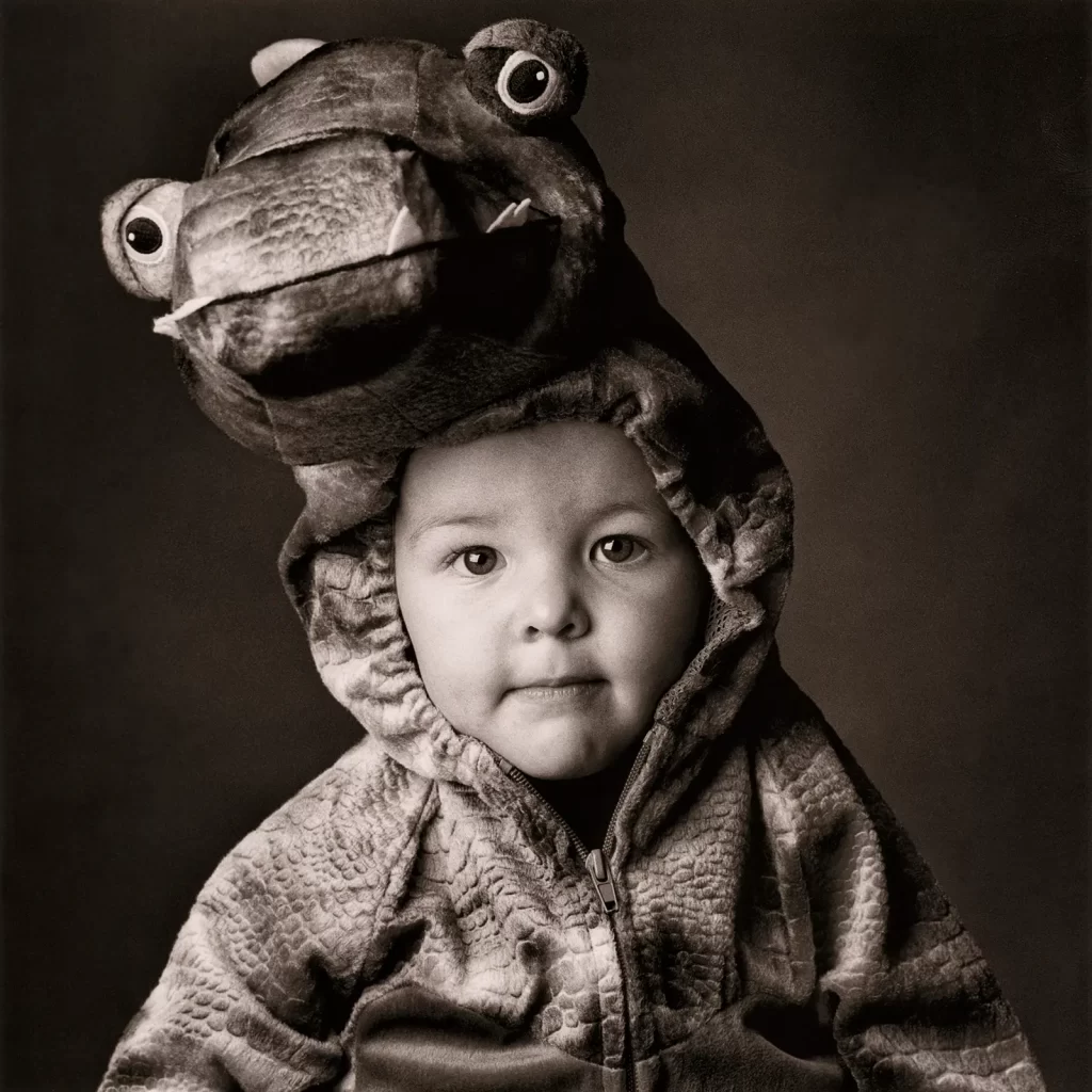 Black and white portrait of a young boy in a dragon costume.