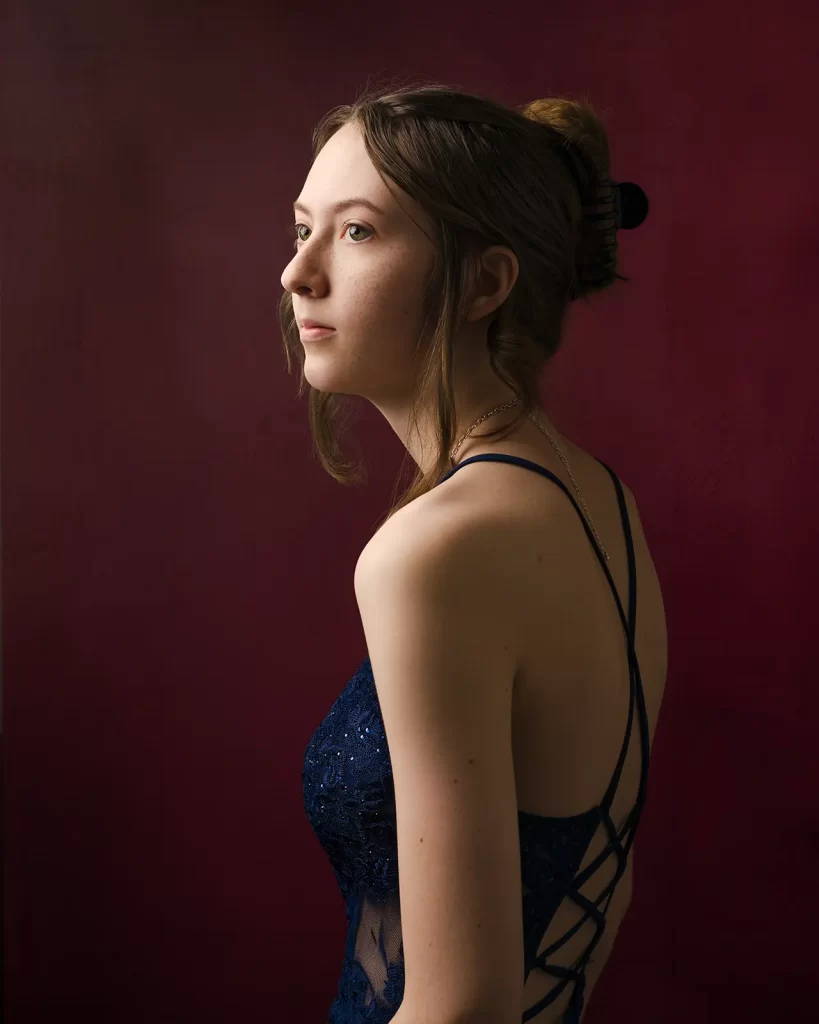 Teenage girl in a blue prom dress on a red background.