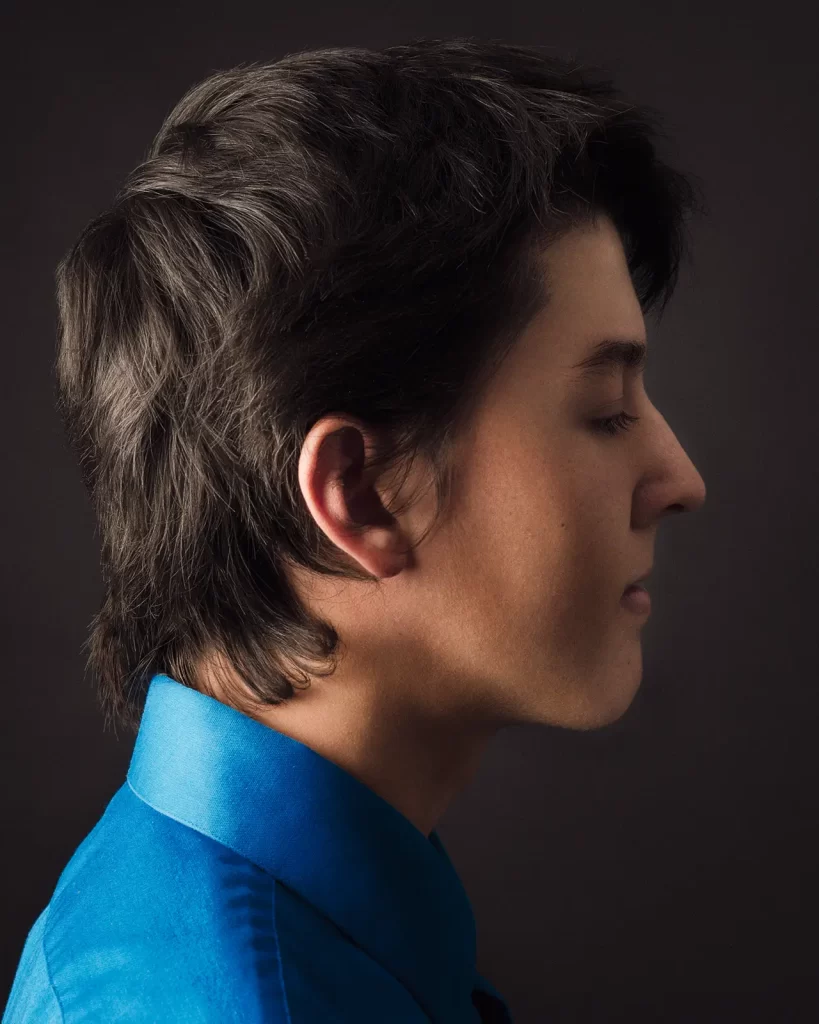 Profile portrait of a teenage boy wearing a bright blue button-down shirt.