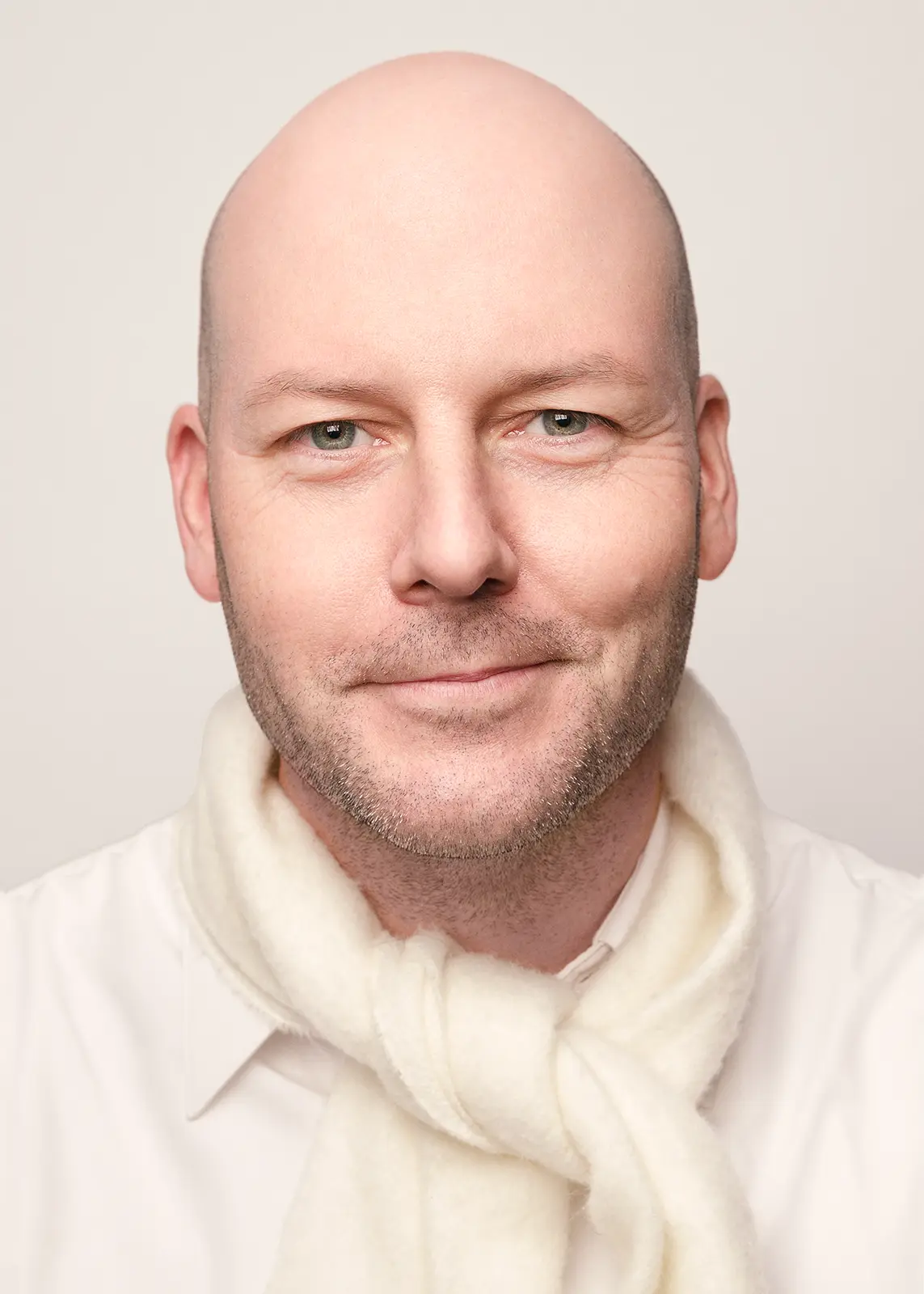 Middle-aged bald man wearing a white scarf on a white background.