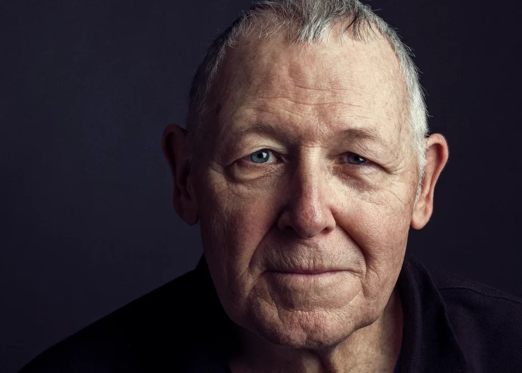 Old man with gray hair and blue eyes on a black background.